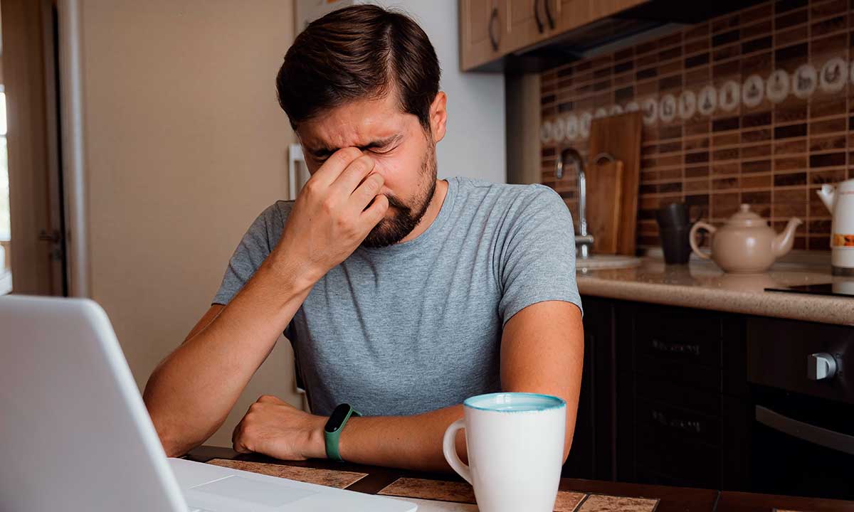 Hombre tocándose la cara por aparente Dolor de cabeza