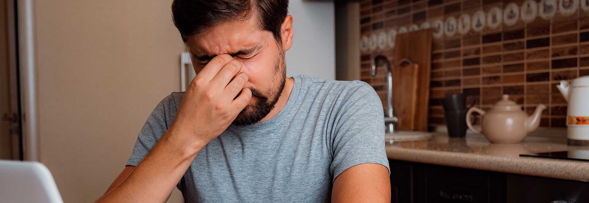 Hombre tocándose la cara por aparente Dolor de cabeza